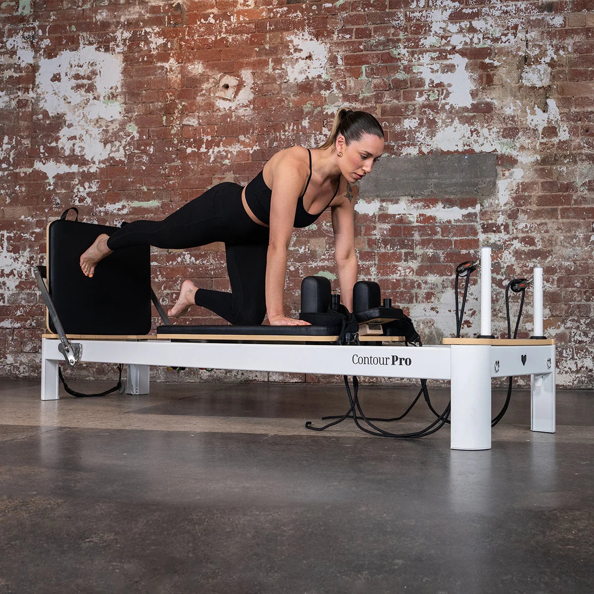 Woman in Workout Clothes Adjusting Reformer Pilates Bed Stock